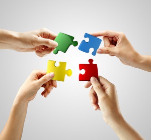 Hands and puzzle on gray background. Teamwork solving a puzzle